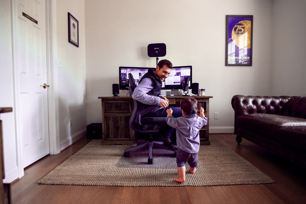 a child toddles toward their parent in a home office